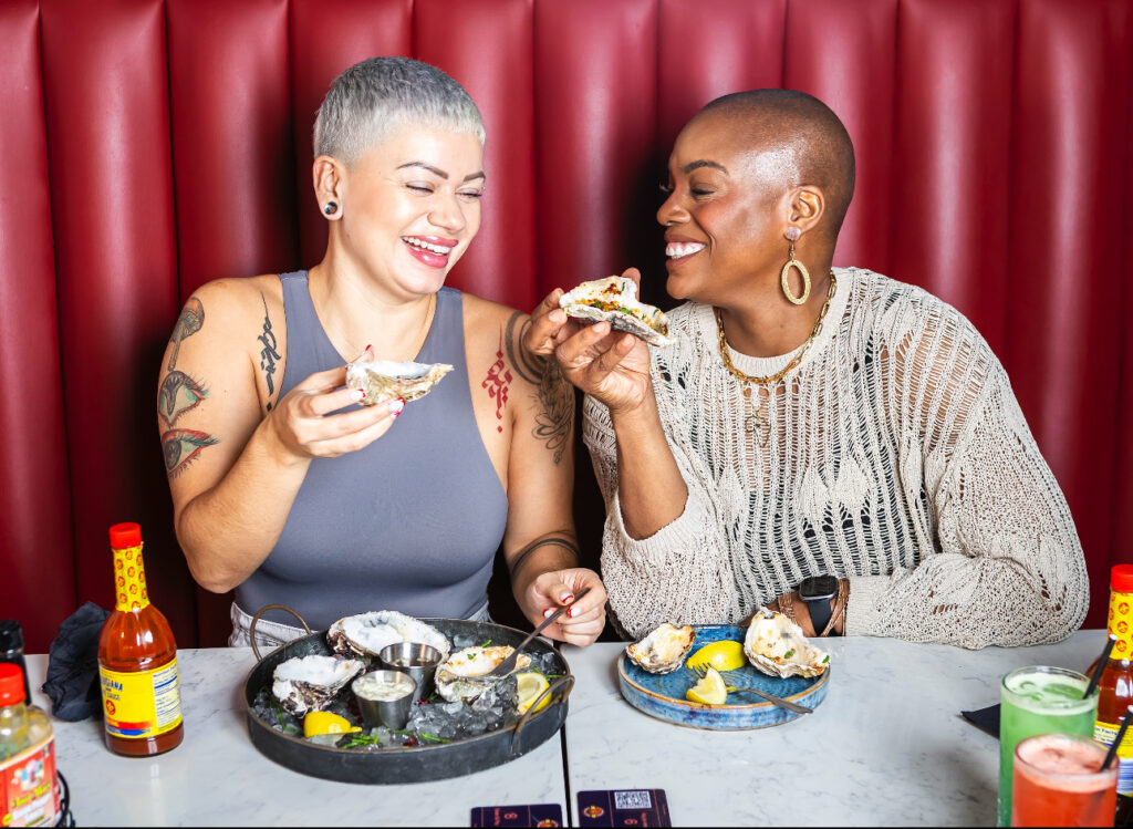 2 women enjoying oysters at hot n juicy shrimp ldn